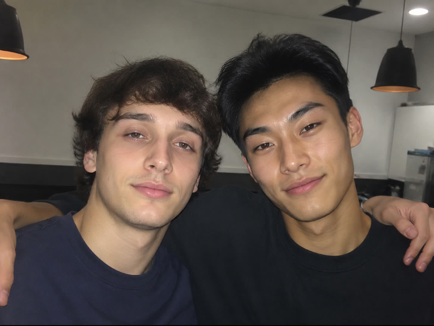 Candid photo of two young men side by side — the man on the left has a flatter, near-neutral eye tilt, and the man on the right has a positive canthal tilt with lifted outer corners that read as sharper